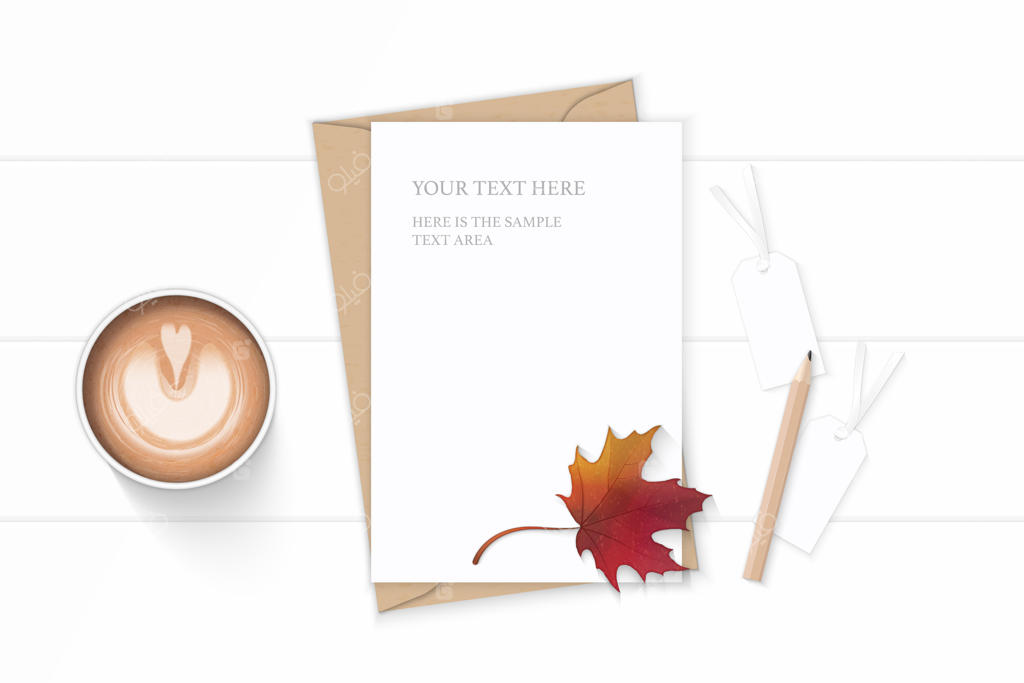 کاغذ نامه روی برگ پاییزی افرا همراه با مداد و قهوه روی میز چوبی